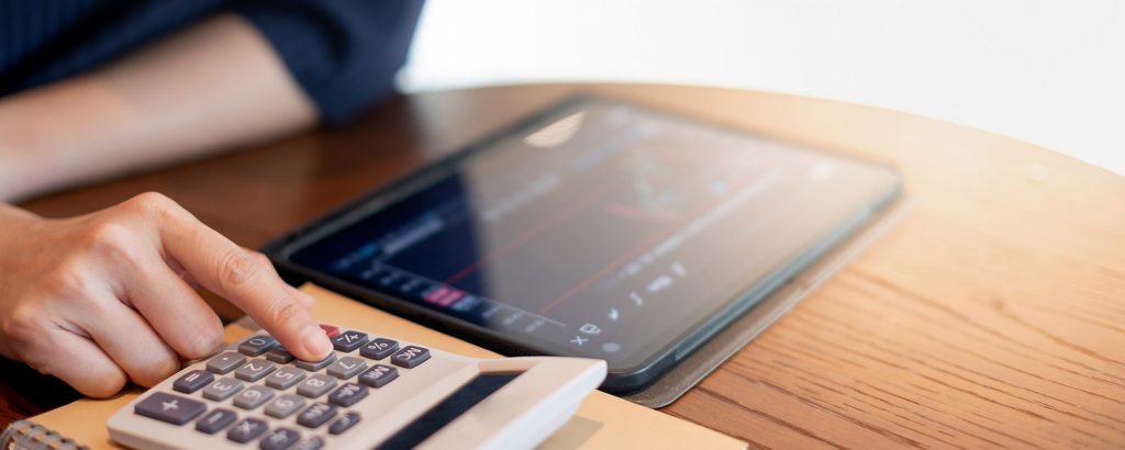 A person using a calculator while looking at a graph on a tablet.
