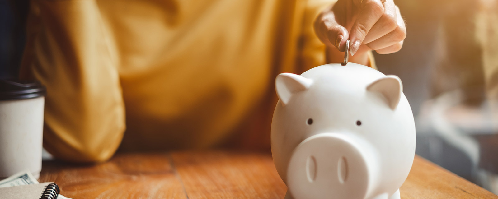 A woman placing a coin in a piggy bank.
